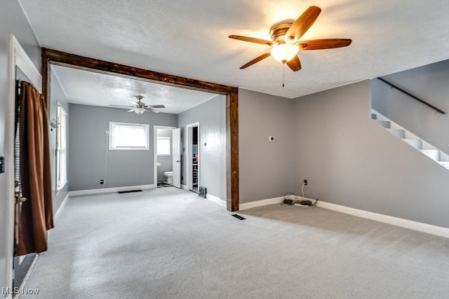 2743 12th St SW, Canton, OH 44710 - unfurnished living room featuring ceiling fan, a textured ceiling, light carpet, baseboards, and stairs