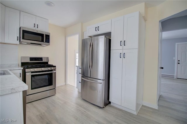 kitchen with white cabinetry, appliances with stainless steel finishes, and light wood-type flooring