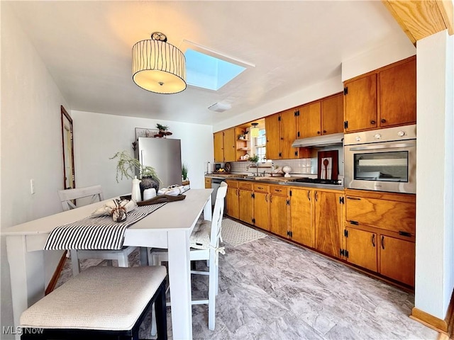 kitchen featuring stainless steel oven, brown cabinets, a skylight, fridge, and open shelves