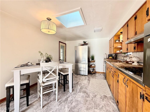 kitchen featuring dark countertops, under cabinet range hood, appliances with stainless steel finishes, a skylight, and open shelves