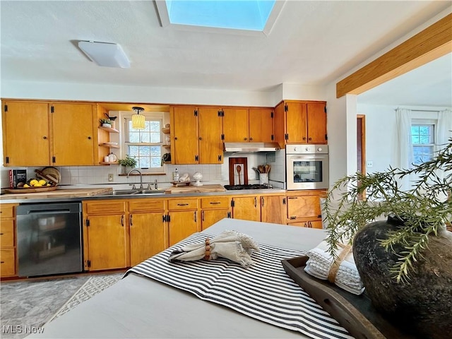 kitchen featuring a sink, backsplash, appliances with stainless steel finishes, and under cabinet range hood