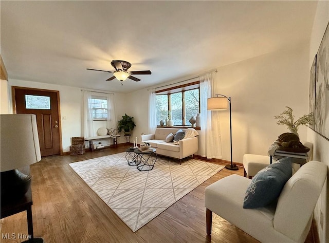 living room featuring wood finished floors, baseboards, and ceiling fan