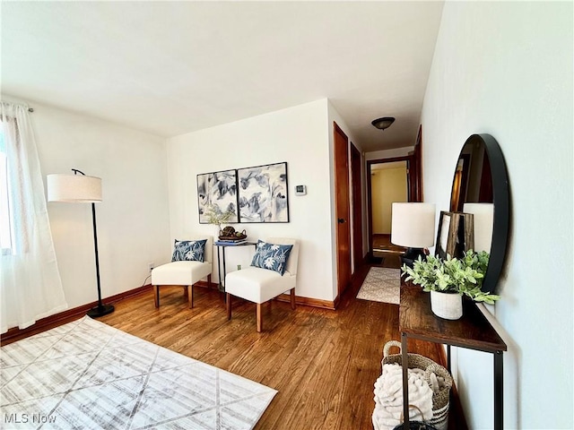 sitting room with baseboards and wood finished floors