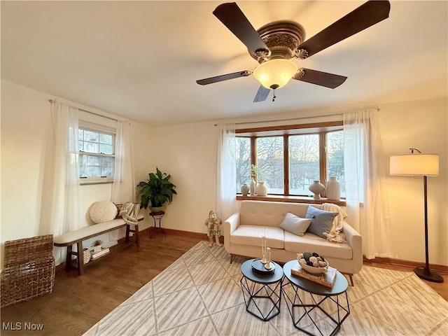 living area featuring a ceiling fan, wood finished floors, and baseboards