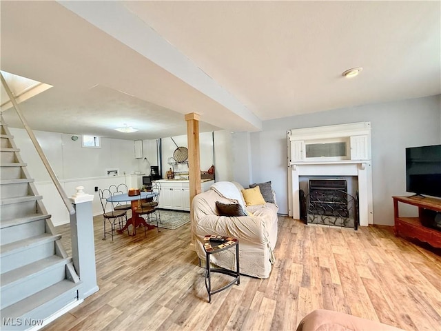 living area with a fireplace, stairway, and light wood-style floors