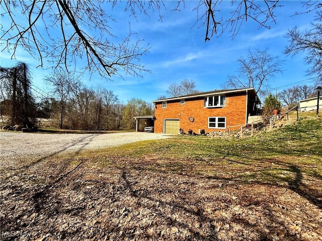 back of property with a garage, brick siding, and driveway