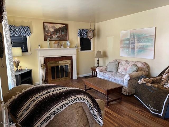 living room featuring dark wood-type flooring and a brick fireplace