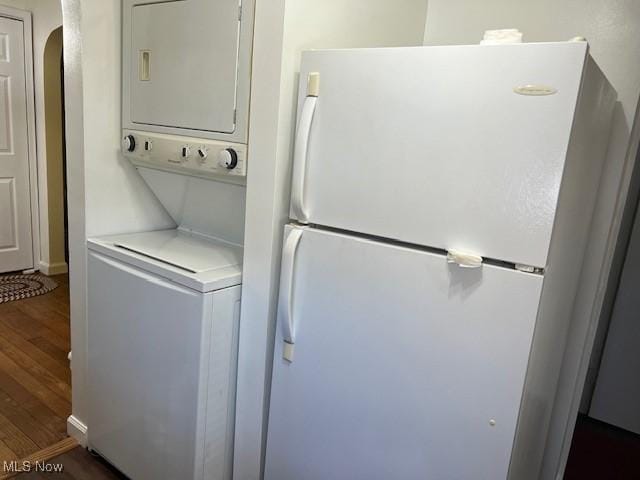 clothes washing area featuring stacked washer / drying machine and dark wood-type flooring