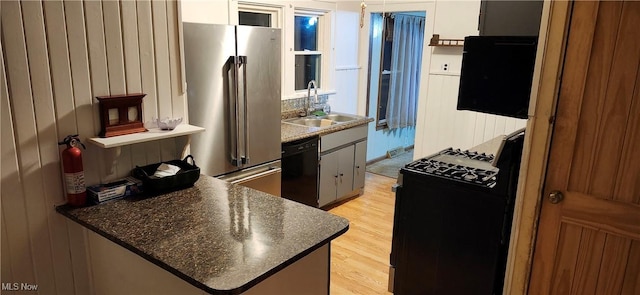 kitchen with high quality fridge, sink, black dishwasher, stove, and light hardwood / wood-style floors