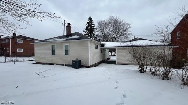 snow covered back of property featuring cooling unit