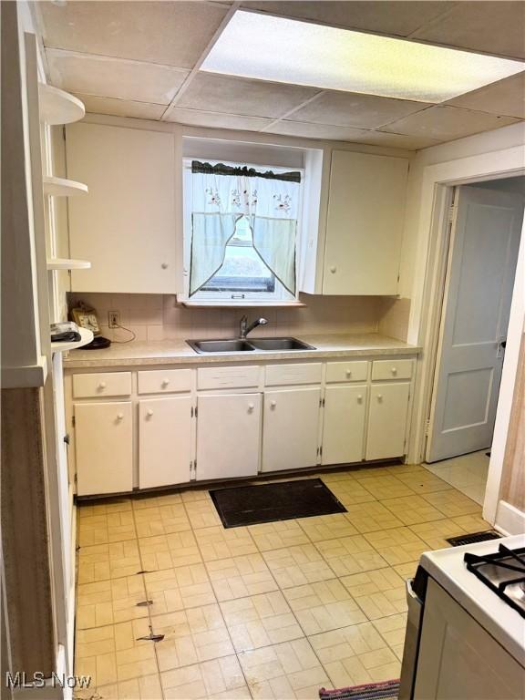 kitchen with sink, white cabinetry, a paneled ceiling, tasteful backsplash, and white range with gas cooktop