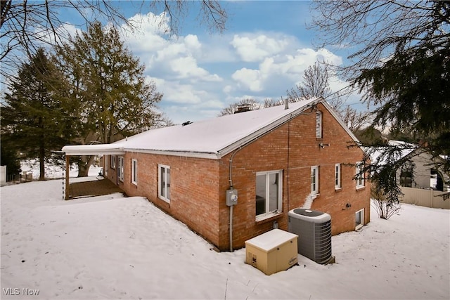 snow covered back of property featuring central AC