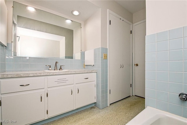 bathroom with vanity and tile walls