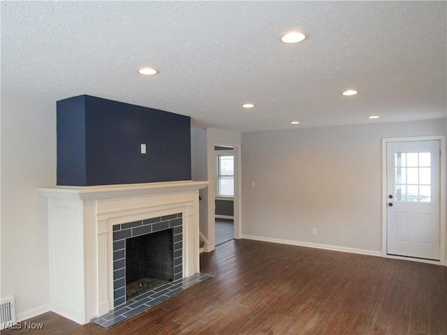 unfurnished living room featuring dark wood-type flooring, a fireplace, and a textured ceiling