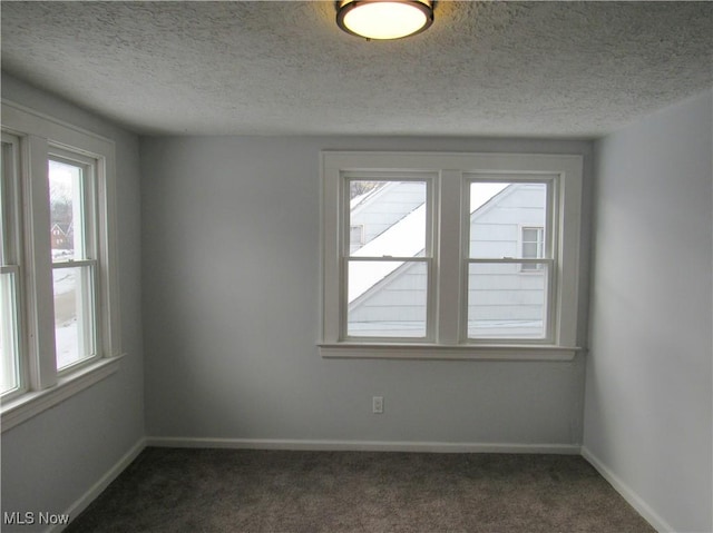 unfurnished room with dark carpet and a textured ceiling