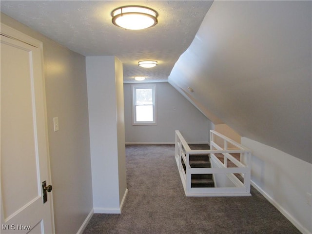 additional living space with lofted ceiling, dark carpet, and a textured ceiling