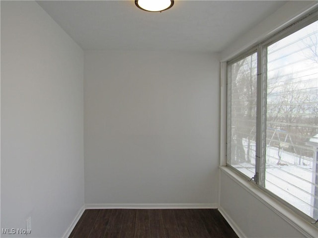 spare room featuring plenty of natural light and dark hardwood / wood-style flooring