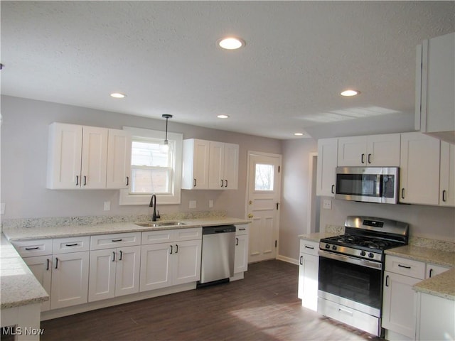 kitchen featuring sink, decorative light fixtures, white cabinets, and appliances with stainless steel finishes