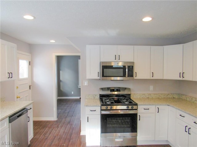 kitchen featuring stainless steel appliances, white cabinetry, hardwood / wood-style flooring, and light stone counters