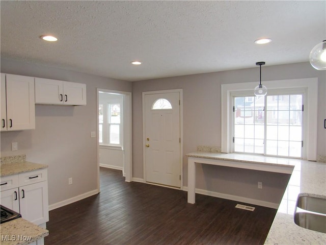 kitchen featuring pendant lighting, white cabinets, dark hardwood / wood-style flooring, light stone countertops, and a textured ceiling