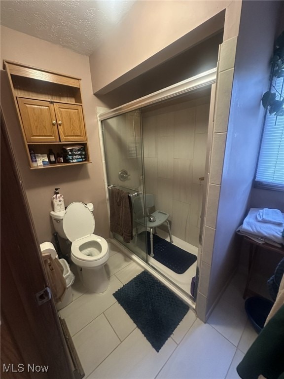 bathroom featuring a shower with door, tile patterned floors, a textured ceiling, and toilet