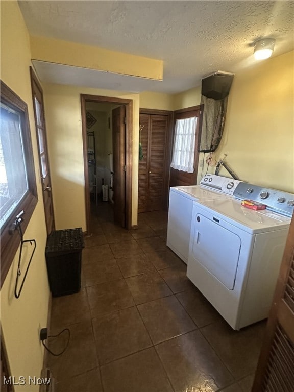 washroom with washer / clothes dryer, a textured ceiling, and dark tile patterned flooring