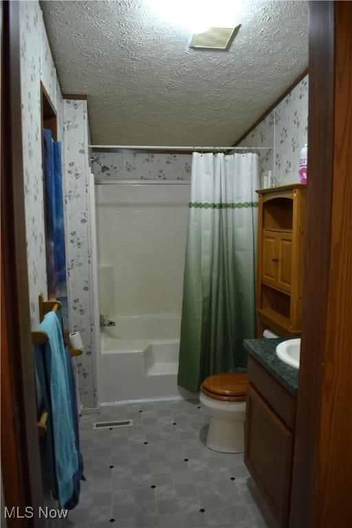 full bathroom with vanity, a textured ceiling, vaulted ceiling, toilet, and shower / bath combo with shower curtain