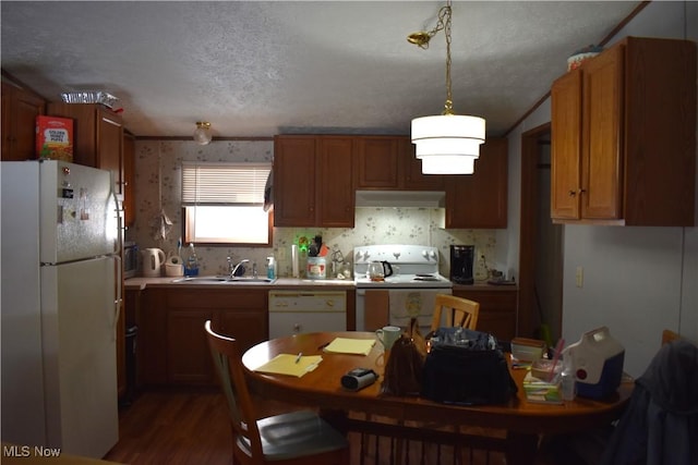 kitchen featuring pendant lighting, sink, white appliances, a textured ceiling, and dark hardwood / wood-style flooring