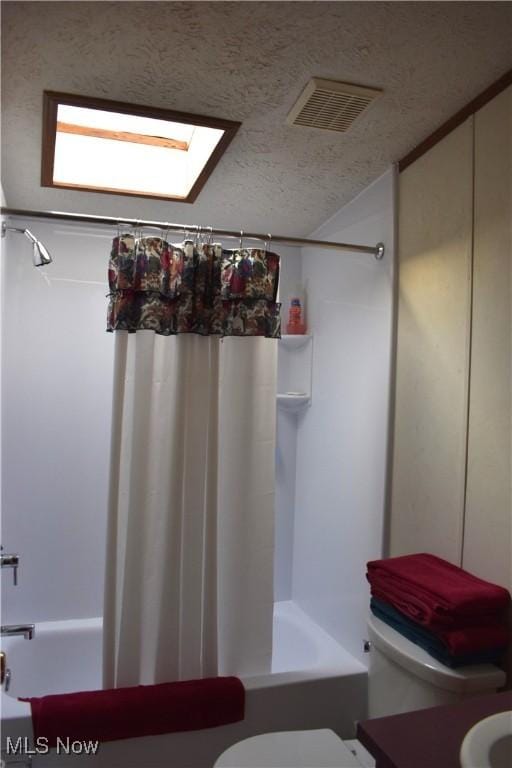 bathroom with toilet, shower / tub combo, a textured ceiling, and a skylight