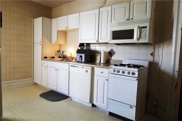 kitchen with sink, backsplash, white cabinets, and white appliances