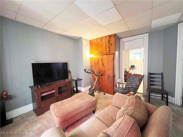 living room with carpet, a drop ceiling, and wooden walls