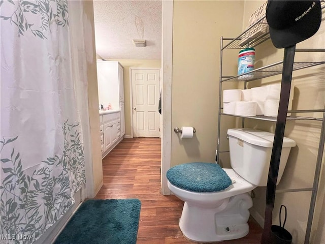 bathroom featuring hardwood / wood-style flooring, vanity, toilet, and a textured ceiling