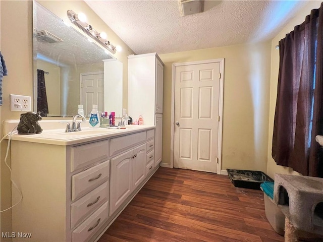 bathroom with hardwood / wood-style flooring, vanity, and a textured ceiling