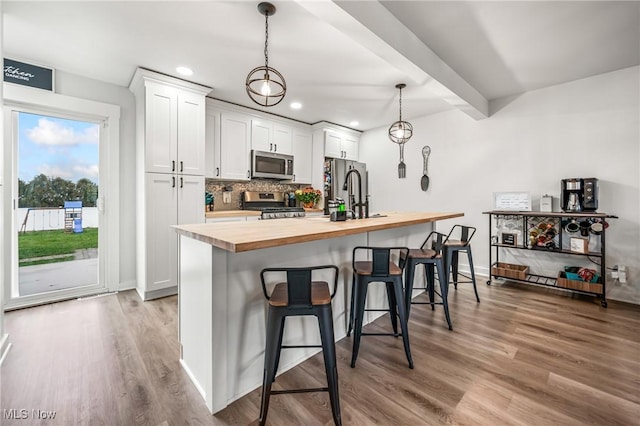 kitchen with white cabinetry, butcher block countertops, stainless steel appliances, and a breakfast bar