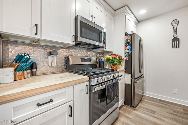 kitchen featuring white cabinetry, decorative backsplash, butcher block counters, and appliances with stainless steel finishes