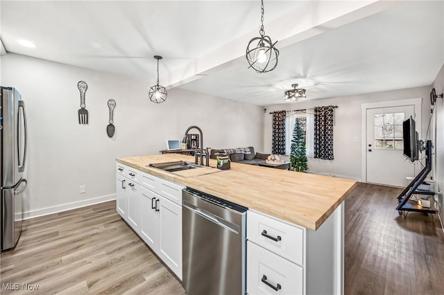 kitchen featuring appliances with stainless steel finishes, pendant lighting, and wood counters