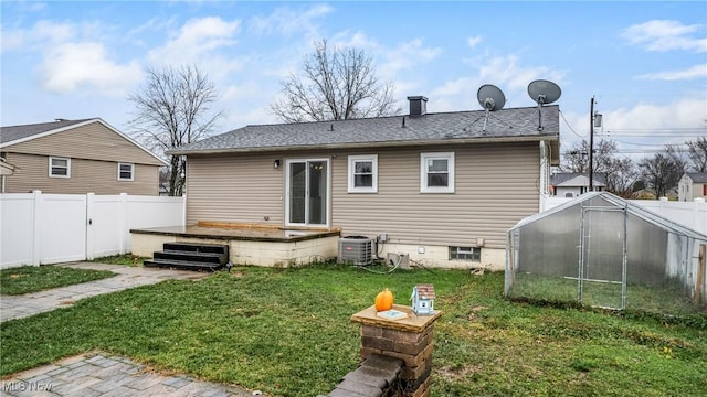 rear view of property with cooling unit, an outdoor structure, a wooden deck, and a lawn