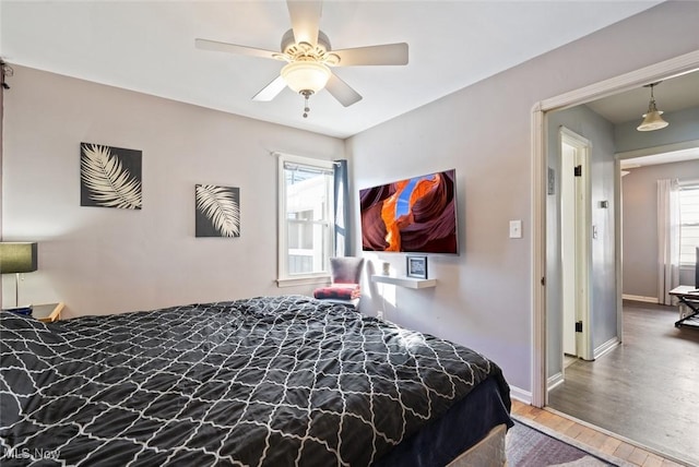 bedroom with multiple windows, hardwood / wood-style flooring, and ceiling fan