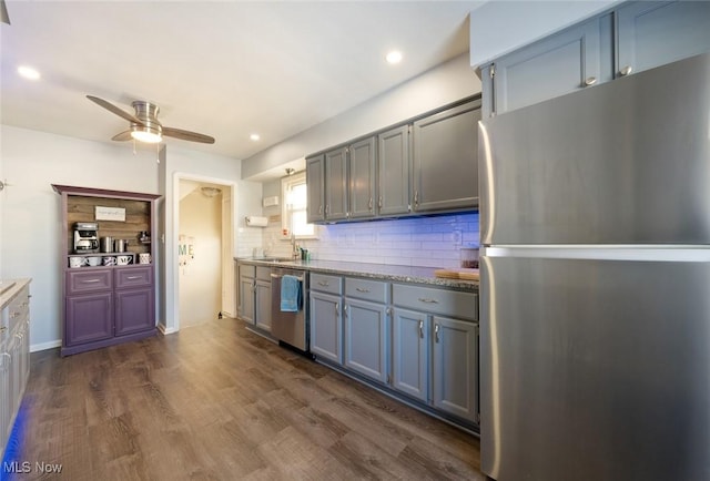 kitchen featuring appliances with stainless steel finishes, sink, dark hardwood / wood-style flooring, decorative backsplash, and ceiling fan