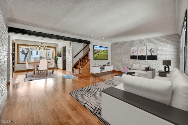 living room with a notable chandelier, brick wall, wood-type flooring, and a textured ceiling