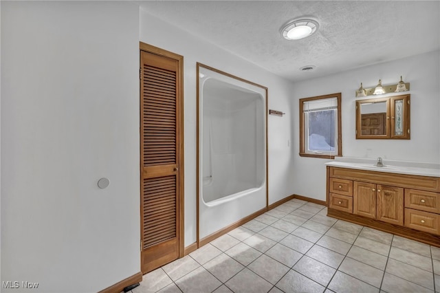 bathroom with tile patterned flooring, vanity, and a textured ceiling