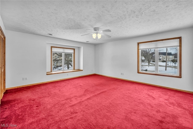 carpeted spare room featuring ceiling fan, plenty of natural light, and a textured ceiling