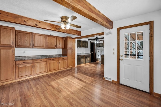 kitchen featuring hardwood / wood-style floors, a textured ceiling, and beam ceiling