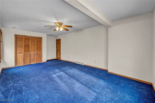 unfurnished bedroom with beamed ceiling, carpet, ceiling fan, and a closet