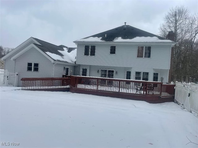 snow covered back of property featuring a deck