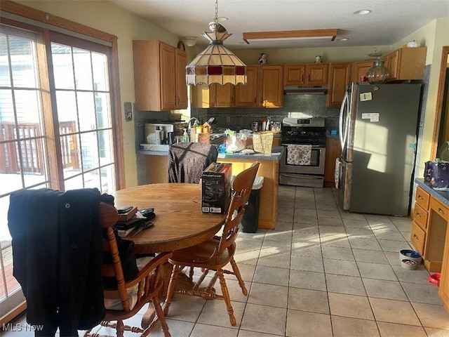 kitchen with tasteful backsplash, light tile patterned flooring, appliances with stainless steel finishes, and decorative light fixtures