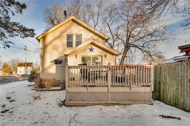 snow covered house featuring a wooden deck