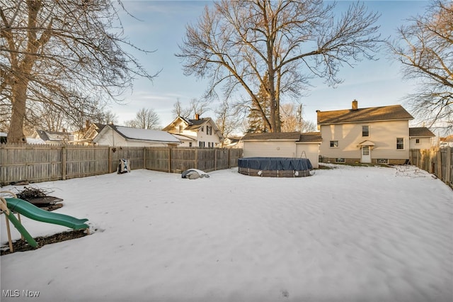 yard layered in snow with a playground and a covered pool