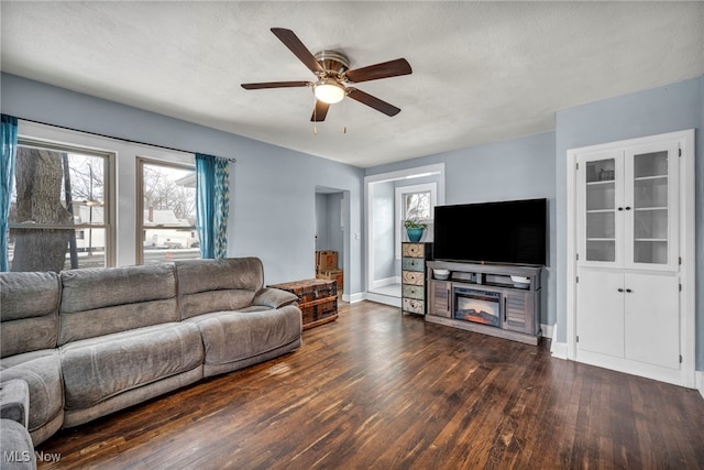 living room featuring ceiling fan, a textured ceiling, and dark hardwood / wood-style flooring