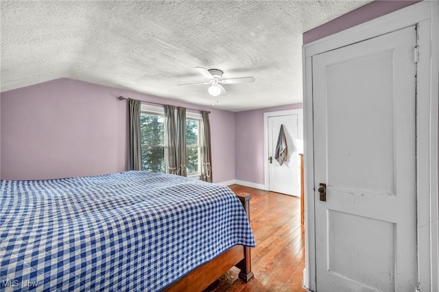 bedroom featuring hardwood / wood-style flooring, vaulted ceiling, a textured ceiling, and ceiling fan